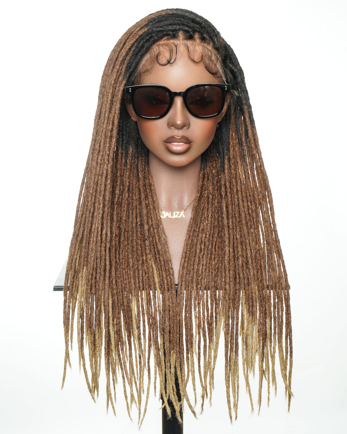 JALIZA 24-inch faux locs ombre wig displayed on a mannequin, featuring black roots fading to brown and blonde ends, pre-bleached Swiss HD full lace frontal, and worn with sunglasses and a JALIZA necklace.